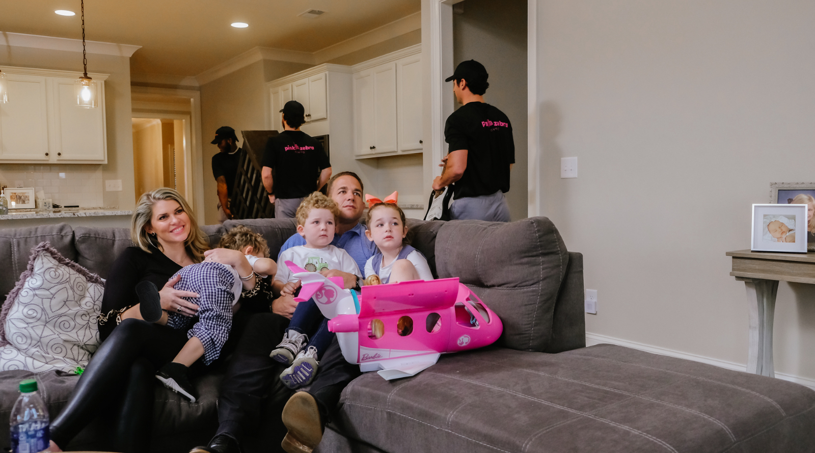 A family relaxing while Pink Zebra movers carefully handle furniture in their home